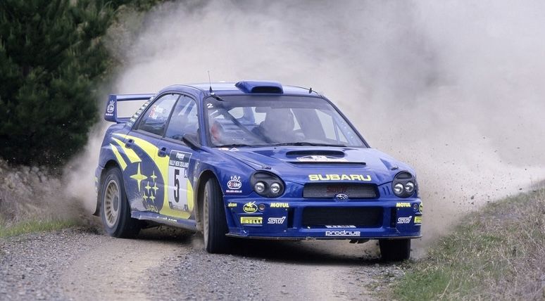 Blue Subaru Impreza WRC rally car, start number 5, on a gravel stage